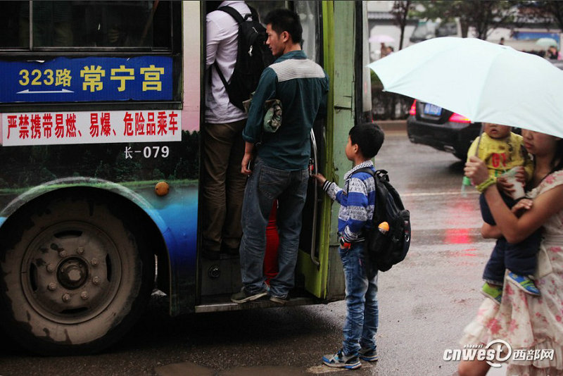 5月17日早高峰，一辆323路公交已挤满了，但一位小学生扔拉着前门把手不愿松开。